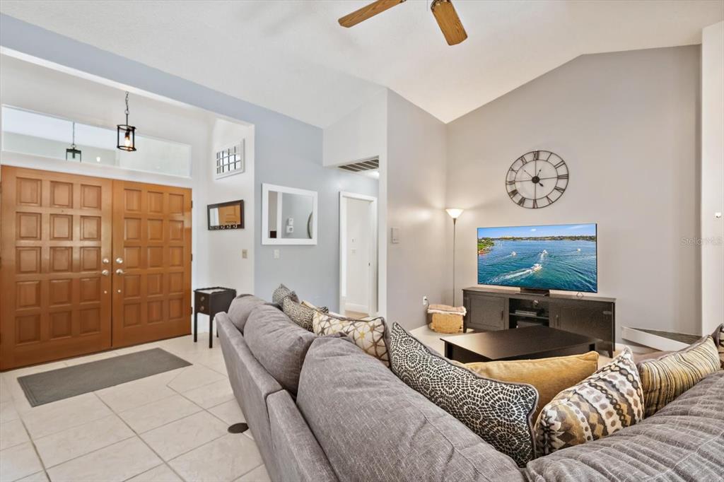 A living room features a gray sectional sofa, a television on a console, and tile flooring — 4732 MEADOWVIEW CIRCLE, SARASOTA, FL