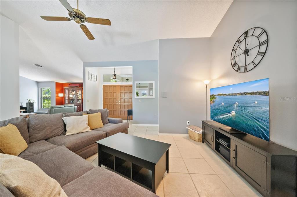 A living room features a gray sectional sofa, a black coffee table, and a large television — 4732 MEADOWVIEW CIRCLE, SARASOTA, FL