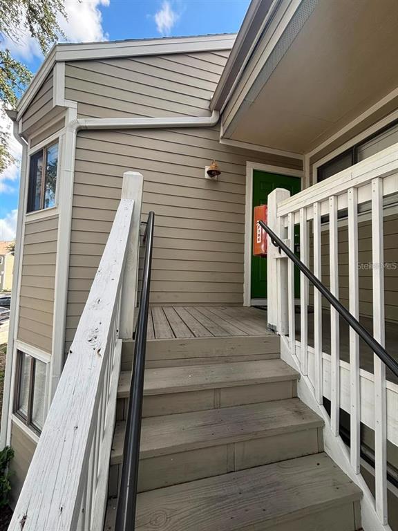 An exterior view of a wooden staircase leading to a green front door — 7298 ULMERTON ROAD UNIT 407, LARGO, FL