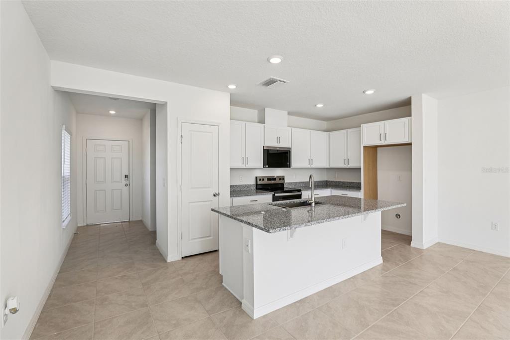 A kitchen with white cabinets, granite countertops, a center island, and tile flooring — 379 SEQUOIA DRIVE, LAKE WALES, FL
