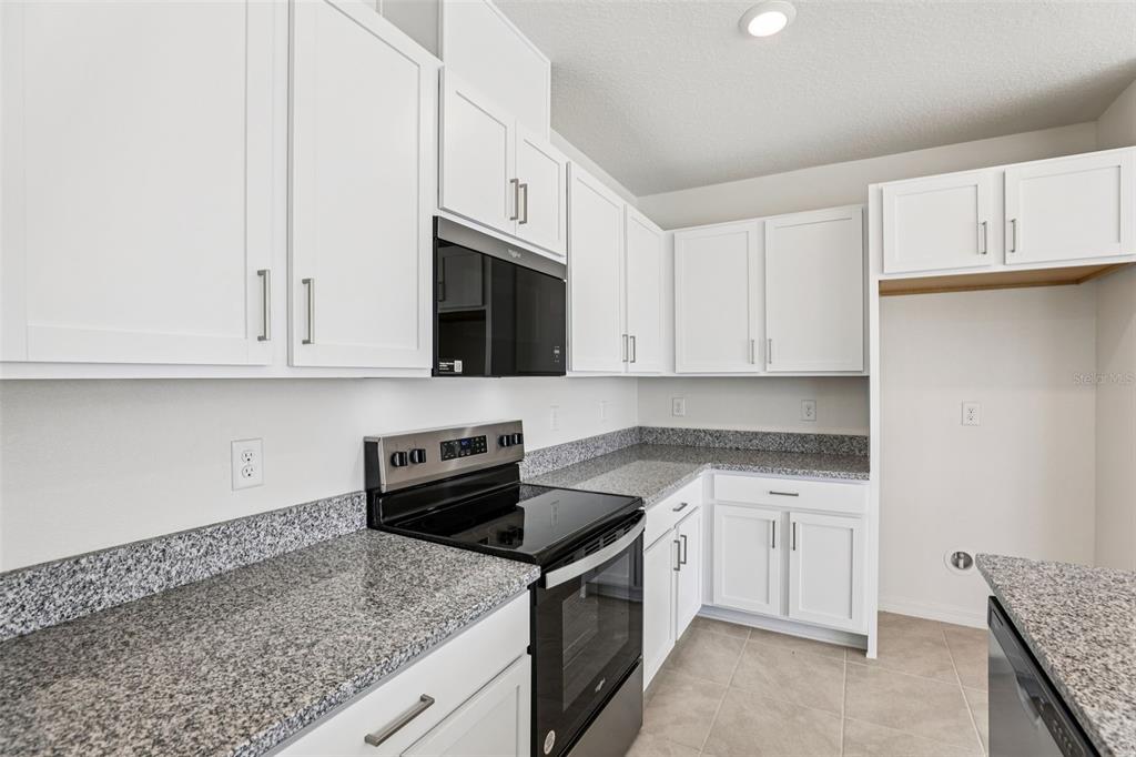 A kitchen features white cabinets, granite countertops, and black appliances — 379 SEQUOIA DRIVE, LAKE WALES, FL