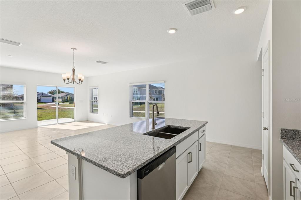 A kitchen island with a granite countertop and stainless steel sink overlooks an open living area — 379 SEQUOIA DRIVE, LAKE WALES, FL