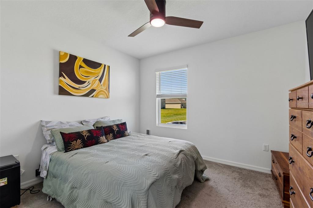 A bedroom features a bed with patterned pillows, a ceiling fan, and a wooden dresser — 3406 GRASSY KNOLL COURT, PLANT CITY, FL