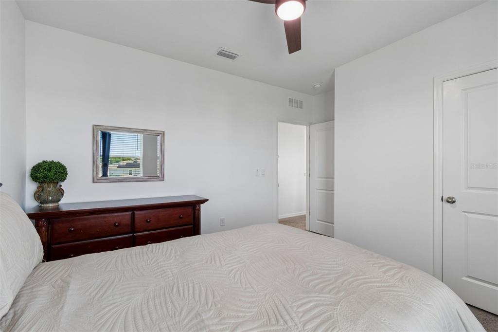 A bedroom features a wooden dresser, a mirror, and a bed with a textured white comforter — 3406 GRASSY KNOLL COURT, PLANT CITY, FL
