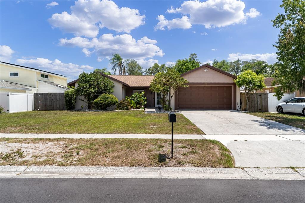 A single-story house with a brown garage door, a concrete driveway, and a front lawn — 6916 WILLIAMS DRIVE, TAMPA, FL