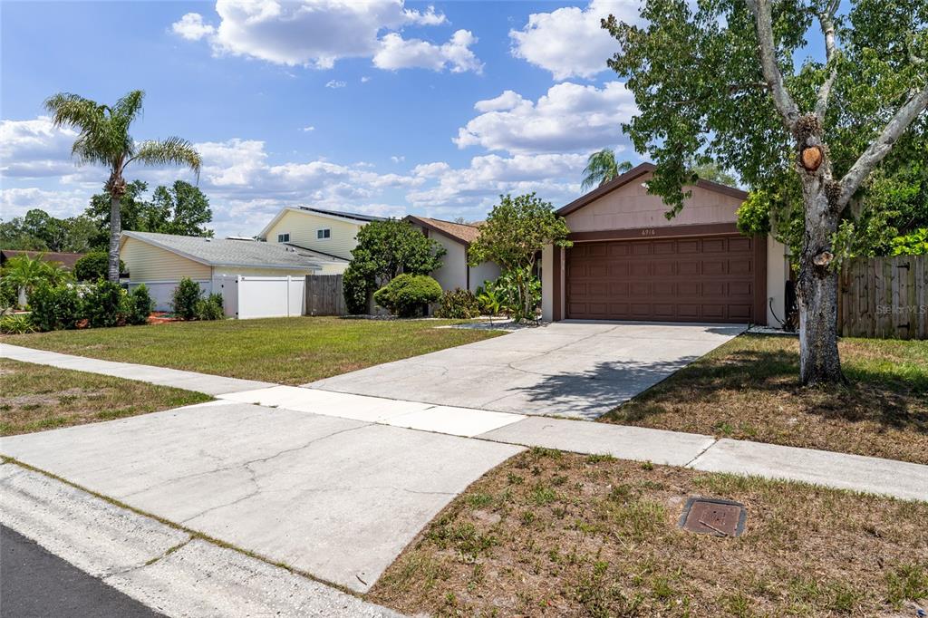 A single-story house with a brown garage door and a concrete driveway under a blue sky — 6916 WILLIAMS DRIVE, TAMPA, FL