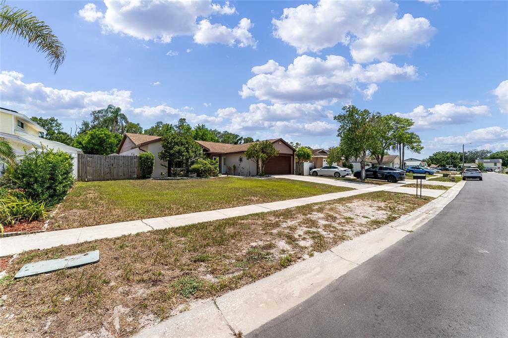 A single-story house with a brown garage and a large front lawn under a sky — 6916 WILLIAMS DRIVE, TAMPA, FL