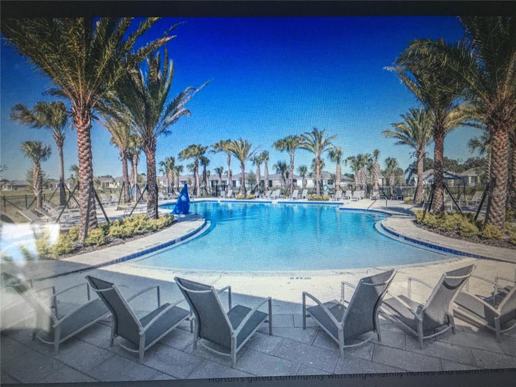 A swimming pool surrounded by palm trees and lounge chairs in a gated community — 7889 PENROSE PLACE, WILDWOOD, FL