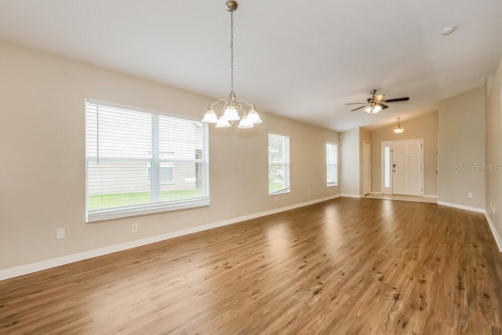 An empty room with light-colored walls, wood-look flooring, a chandelier, and a front entryway — 12706 WHITE BLUFF ROAD, HUDSON, FL
