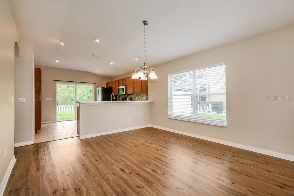 A dining area with wood-look flooring, a chandelier, and an open kitchen with wood cabinets — 12706 WHITE BLUFF ROAD, HUDSON, FL