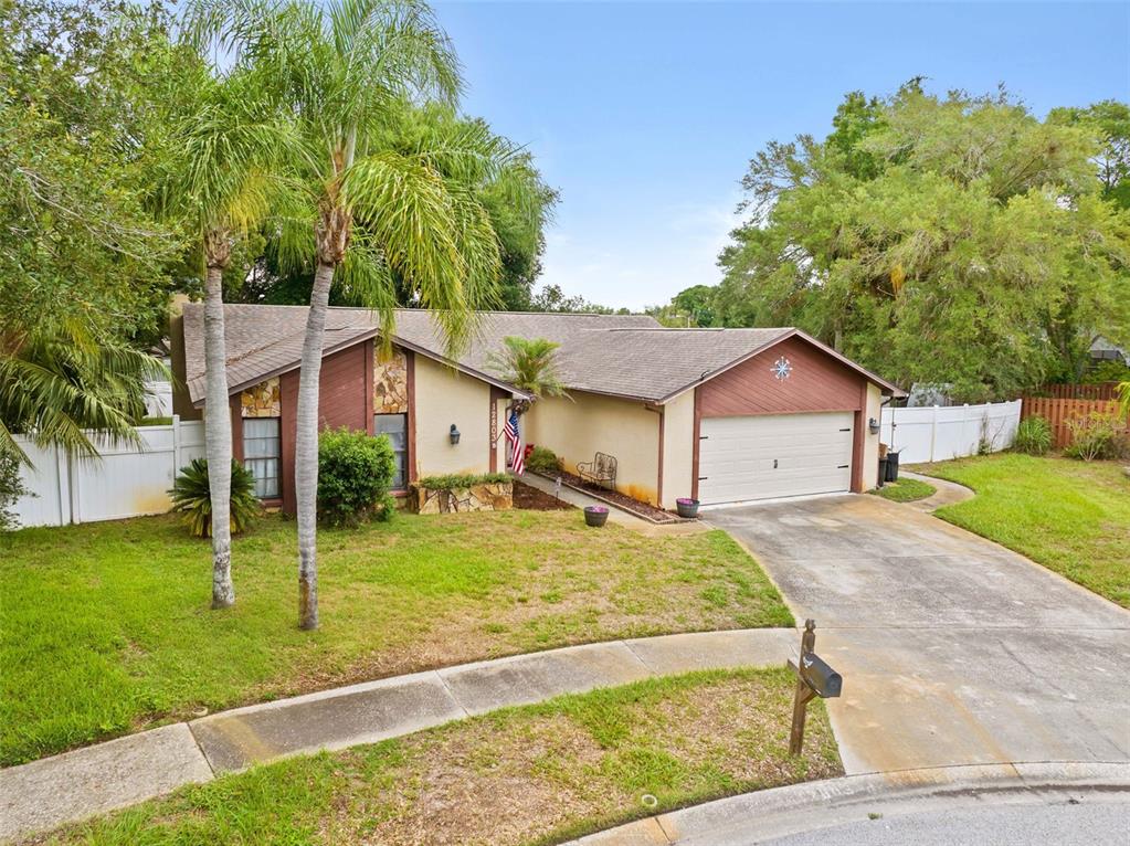 A single-story house with a two-car garage, brown trim, and palm trees in the front yard — 12803 RED MAPLE COURT, HUDSON, FL