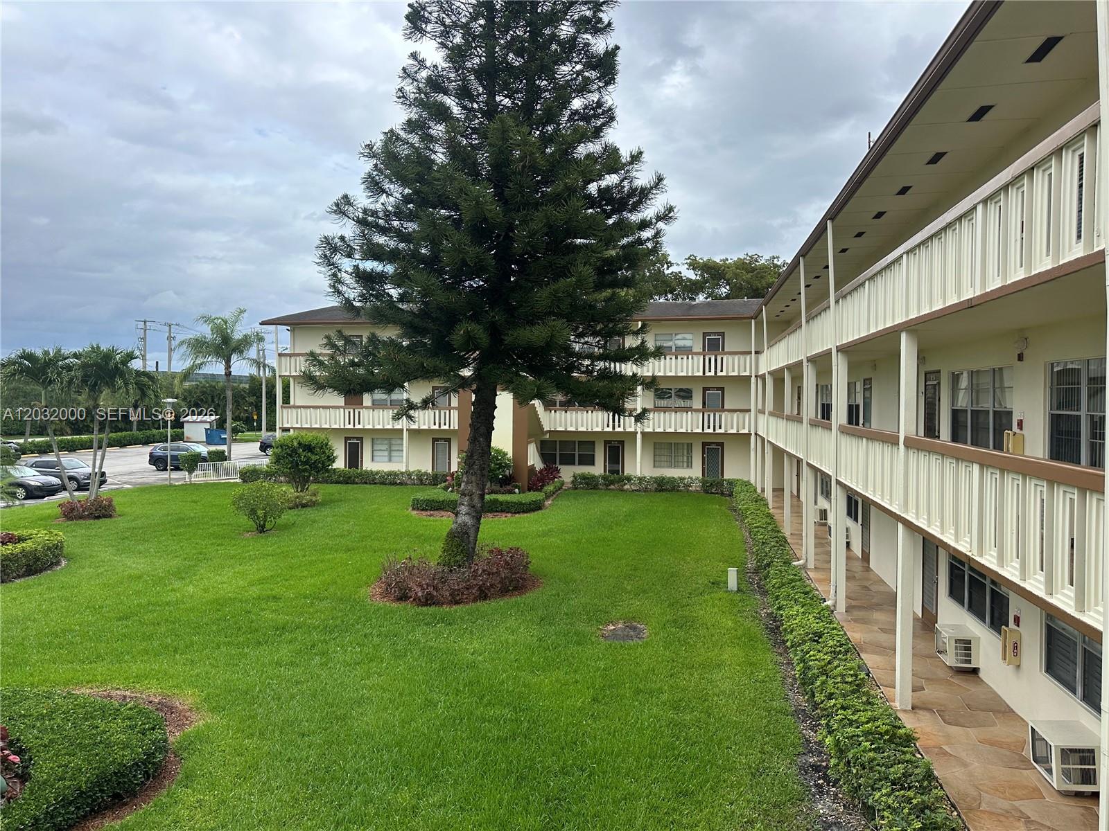 An exterior view of a multi-story apartment building with balconies overlooking a grassy courtyard — 445 Mansfield K # 445, Boca Raton FL 33434, BOCA RATON, FL