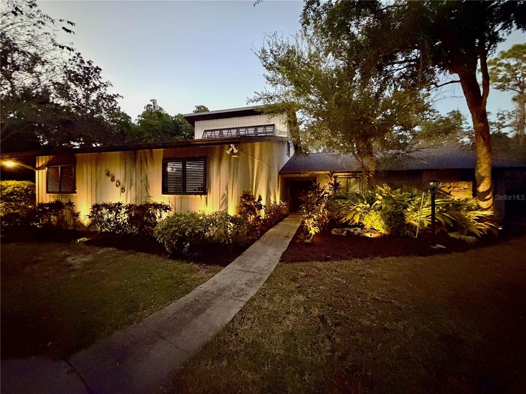 A mid-century modern house exterior with vertical siding, a flat roof, and landscape lighting — 4605 STONE RIDGE TRAIL, SARASOTA, FL