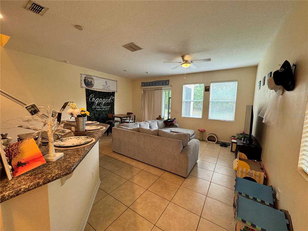 A living room features tile flooring, a gray sectional sofa, and a granite-topped breakfast bar — 1548 PURPLE PLUM LANE, OVIEDO, FL