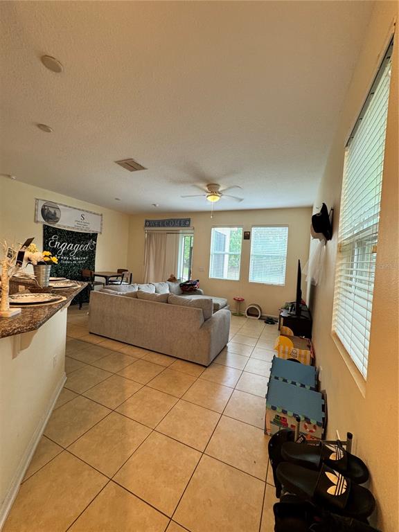 A living room with tile flooring, a gray sectional sofa, and a ceiling fan — 1548 PURPLE PLUM LANE, OVIEDO, FL