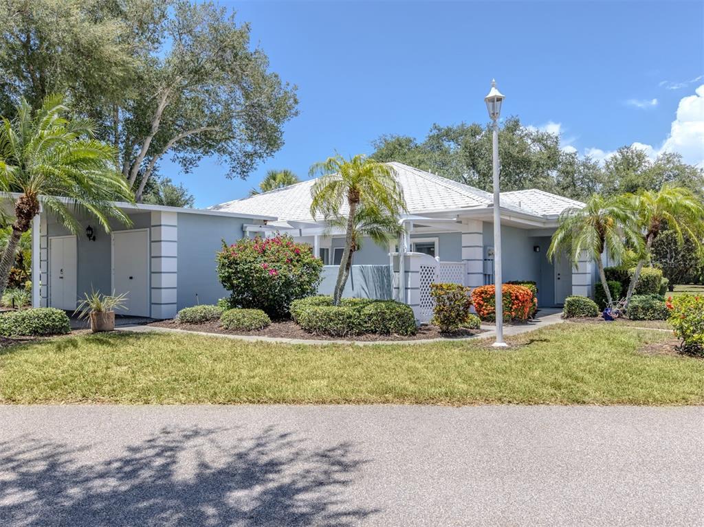 A light blue single-story house features a white roof, palm trees, and a street lamp — 431 WEXFORD CIRCLE UNIT 76, VENICE, FL
