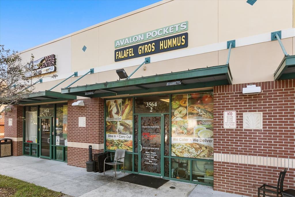 The exterior of a commercial storefront features a brick facade, green awnings, and large glass windows — 3564 AVALON PARK BOULEVARD, ORLANDO, FL