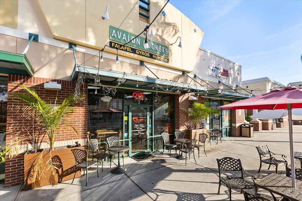 An exterior view of a restaurant storefront with outdoor seating and a red umbrella — 3564 AVALON PARK BOULEVARD, ORLANDO, FL