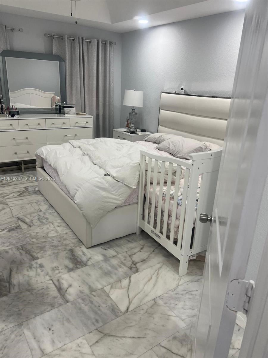 A bedroom features a white bed with an attached crib, a dresser, and marble flooring — 4301 SW 160th Ave # 215, Miramar FL 33027, MIRAMAR, FL