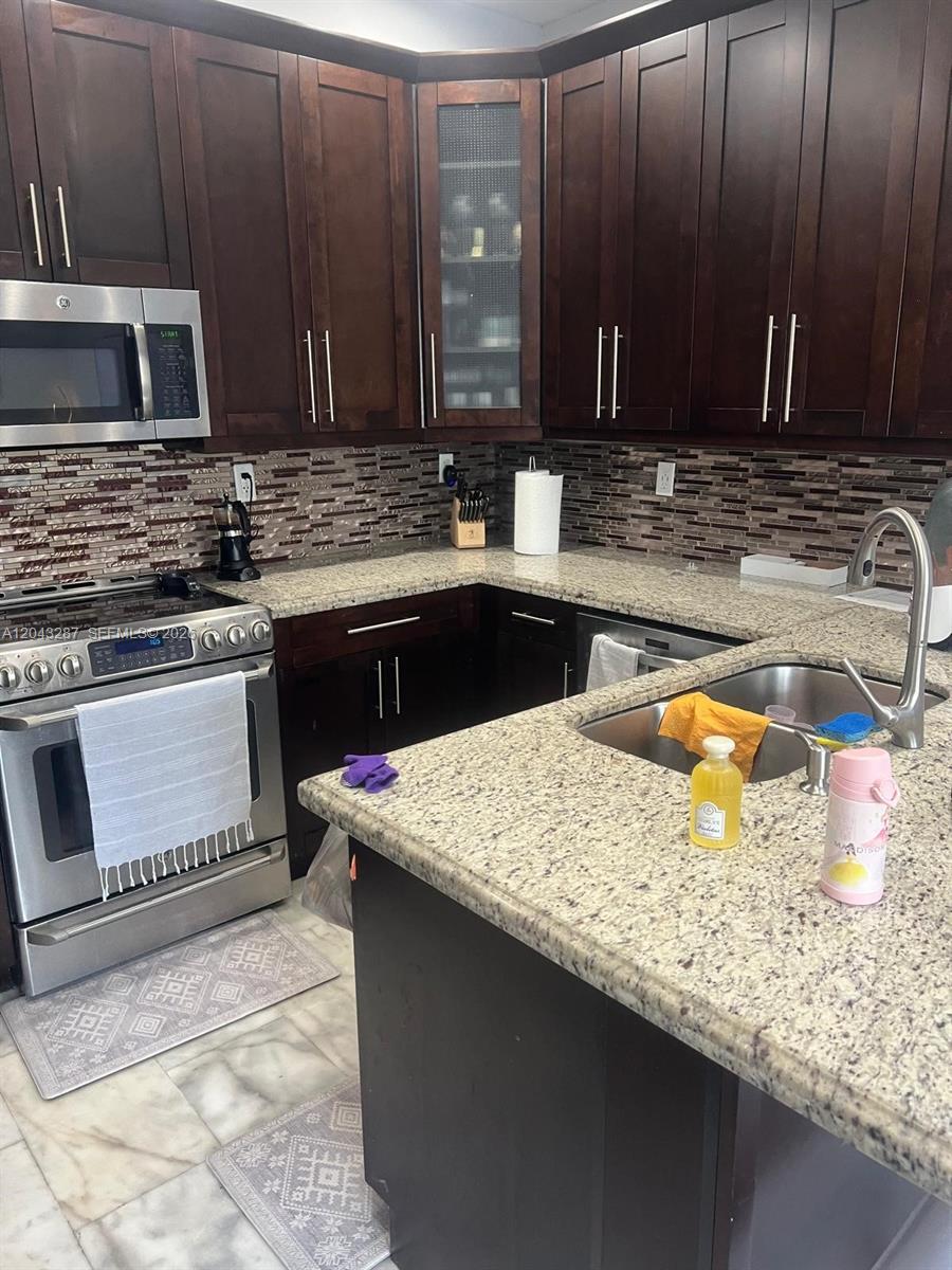 A kitchen features dark wood cabinets, granite countertops, stainless steel appliances, and a tiled backsplash — 4301 SW 160th Ave # 215, Miramar FL 33027, MIRAMAR, FL