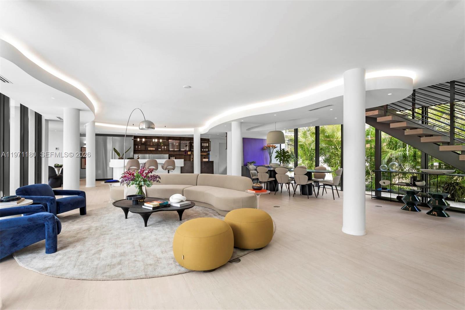 A modern open-concept living and dining area features curved walls, recessed lighting, and a staircase — 5261 NE 5th Ave, Miami FL 33137, MIAMI, FL