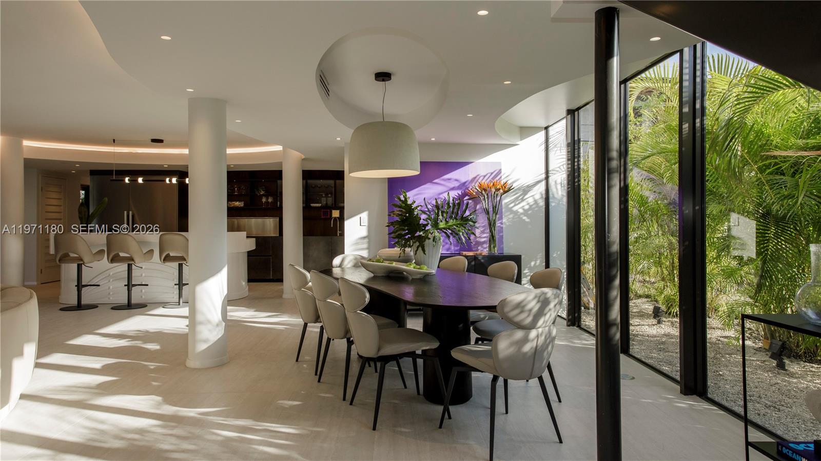 A modern dining room features a dark oval table, light chairs, and floor-to-ceiling windows — 5261 NE 5th Ave, Miami FL 33137, MIAMI, FL