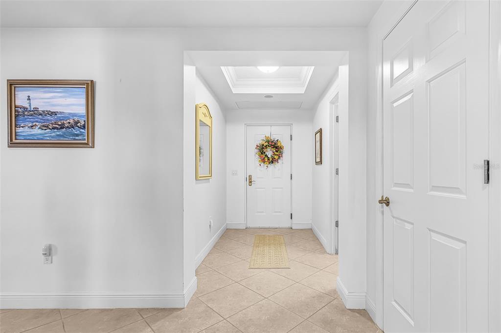 A bright entryway features tiled floors, a white front door with a wreath, and wall art — 3321 SUNSET KEY CIRCLE UNIT 309, PUNTA GORDA, FL