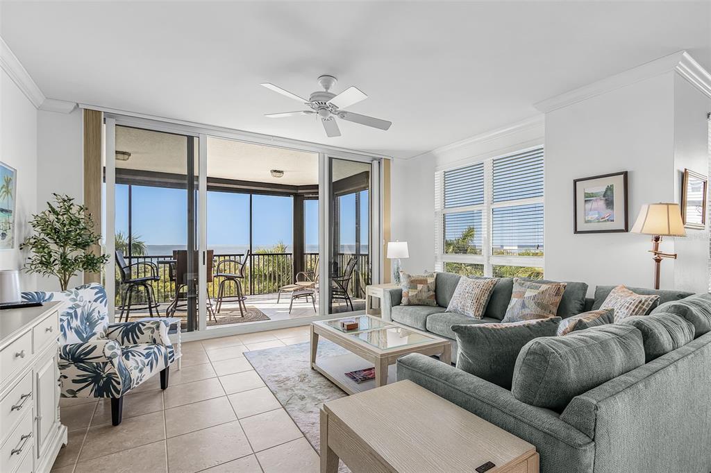 A living room with tile floors, a gray sectional sofa, and a balcony overlooking water — 3321 SUNSET KEY CIRCLE UNIT 309, PUNTA GORDA, FL