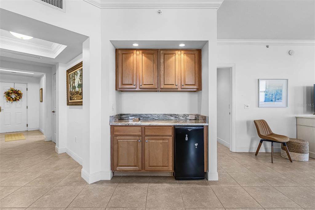 A wet bar features wood cabinets, a granite countertop, and a small black refrigerator — 3321 SUNSET KEY CIRCLE UNIT 309, PUNTA GORDA, FL