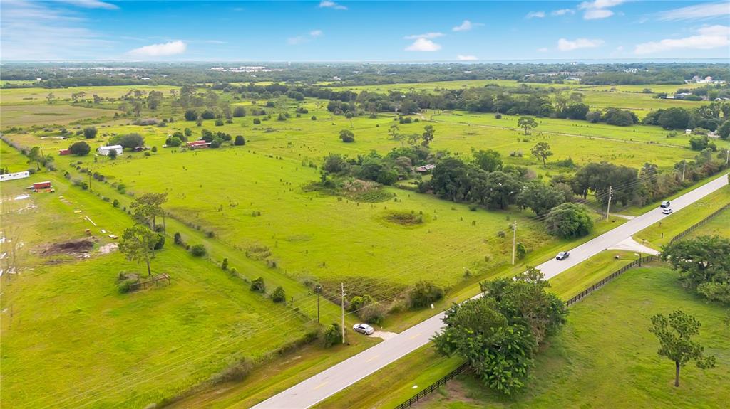 An aerial view shows a large, grassy rural lot bordered by a paved road — OLD HICKORY TREE ROAD, ST CLOUD, FL