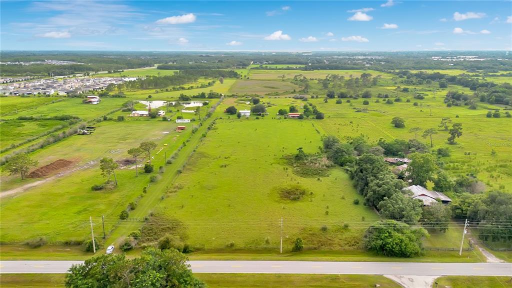 An aerial view of a large, grassy rural lot with scattered trees and several small buildings — OLD HICKORY TREE ROAD, ST CLOUD, FL