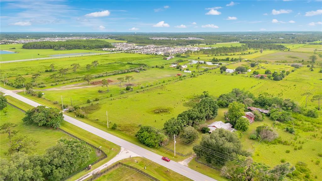 An aerial view shows a rural property with a house, trees, and open fields — OLD HICKORY TREE ROAD, ST CLOUD, FL