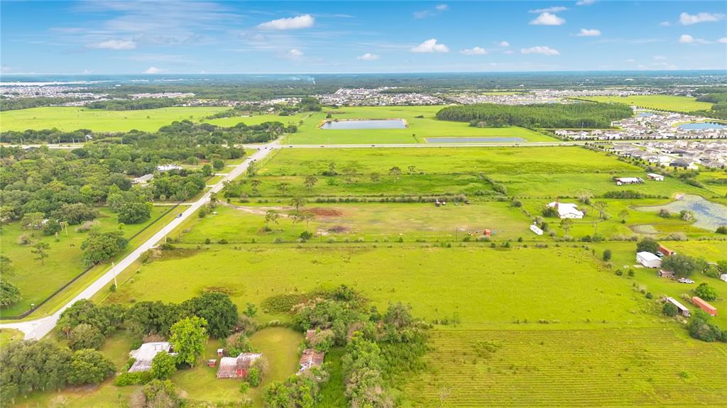 An aerial view shows a large, grassy rural property with several small buildings and trees — OLD HICKORY TREE ROAD, ST CLOUD, FL