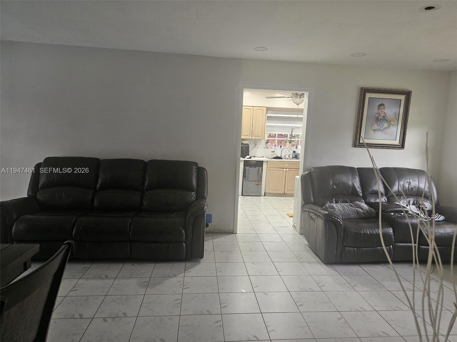 Two dark leather sofas sit on a tiled floor in a living room with a kitchen doorway — 8930 SW 197th Ter, Cutler Bay FL 33157, CUTLER BAY, FL