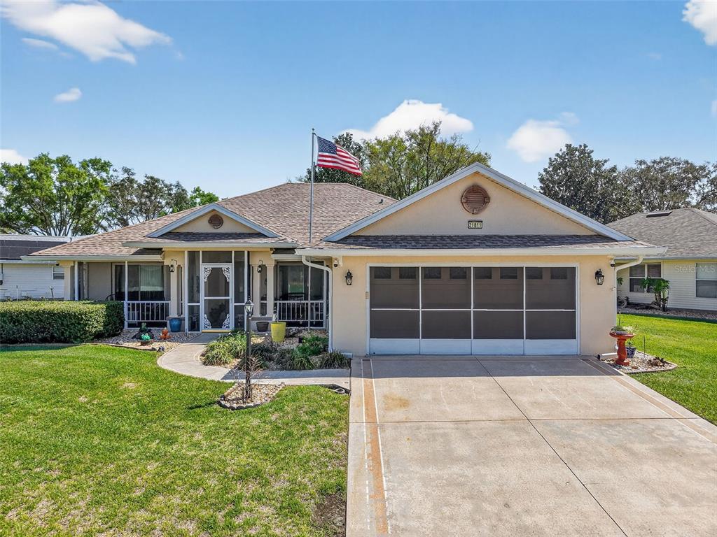 A single-story house with a beige exterior, a screened-in porch, and a two-car garage — 21811 KING HENRY AVENUE, LEESBURG, FL