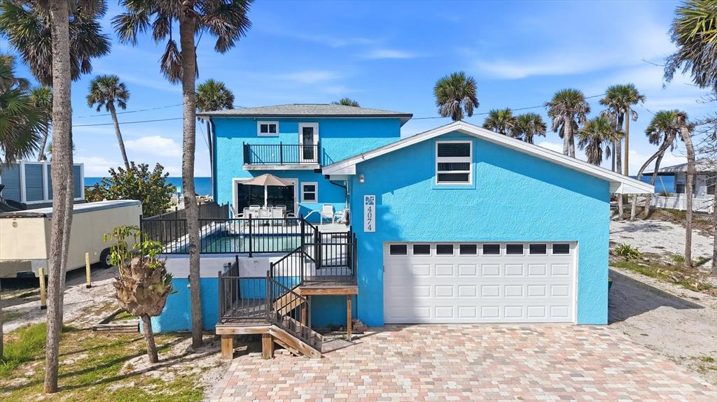 A bright blue two-story house features a swimming pool, a garage, and palm trees — 4074 N BEACH ROAD, ENGLEWOOD, FL