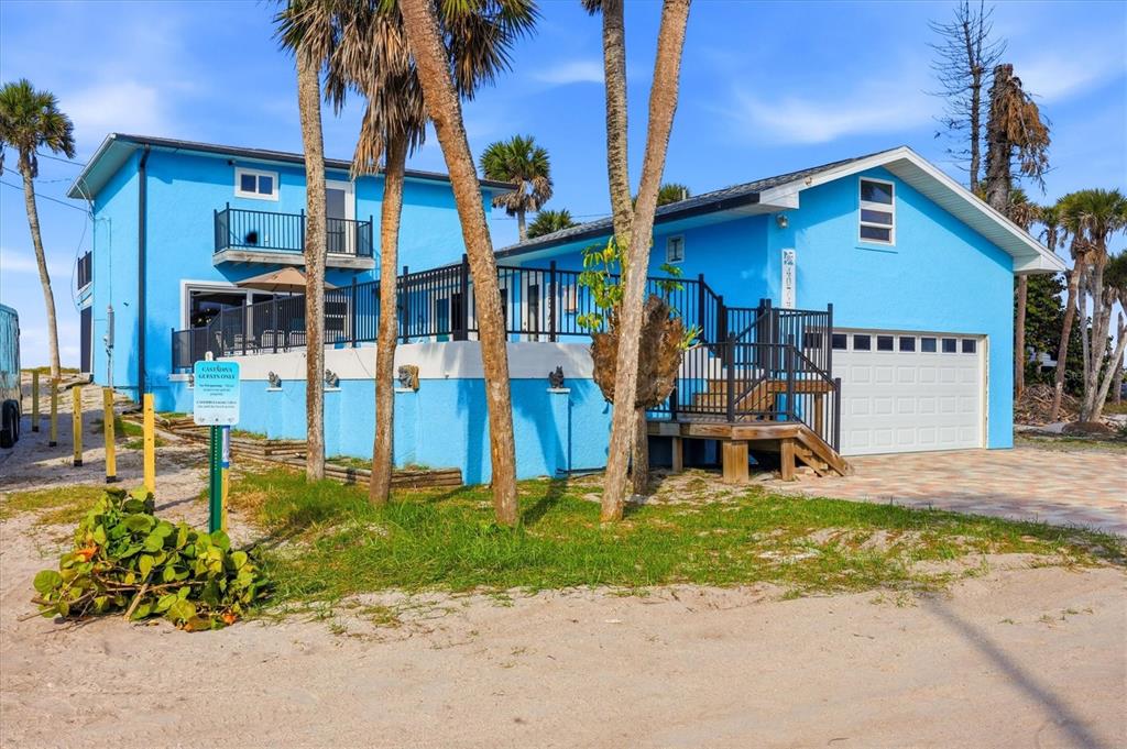 A bright blue two-story house with a garage, deck, and palm trees on a sandy lot — 4074 N BEACH ROAD, ENGLEWOOD, FL