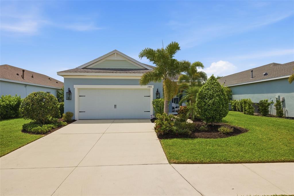 A light blue single-story house features a two-car garage and a landscaped front yard — 13860 OLD CREEK COURT, PARRISH, FL