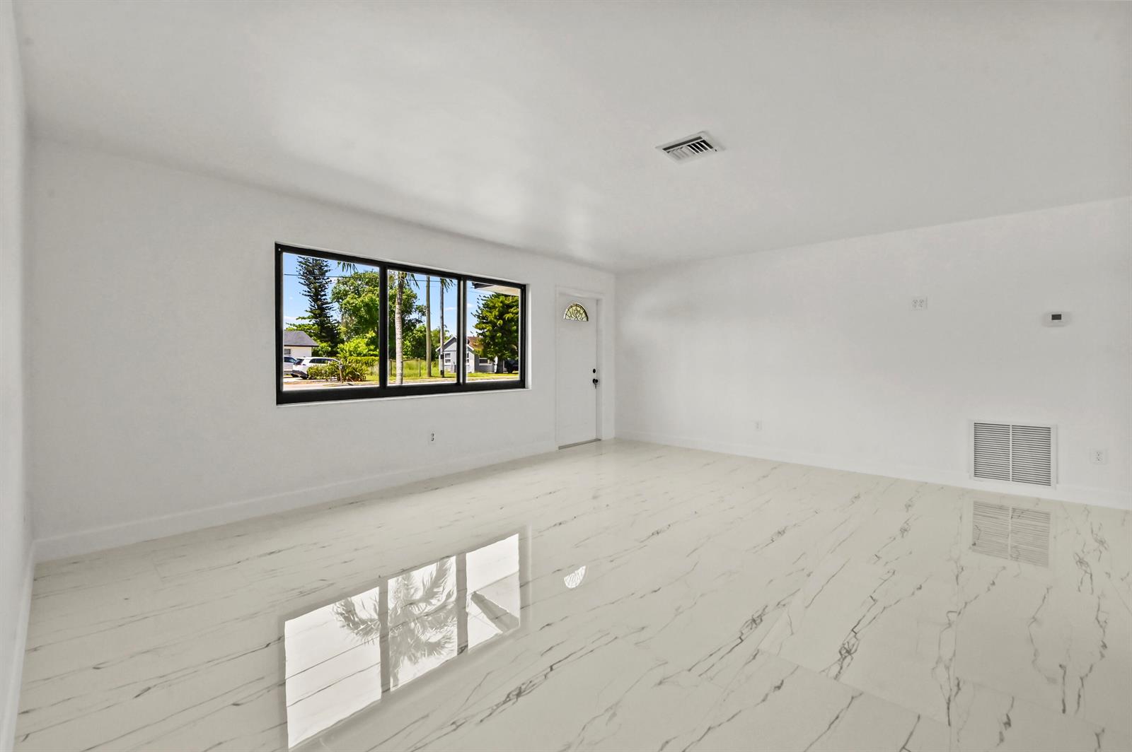 A bright, empty room features white walls, marble-patterned tile flooring, and a large black-framed window — 3645 Melaleuca Lane, Lake Worth FL 33461, LAKE WORTH, FL