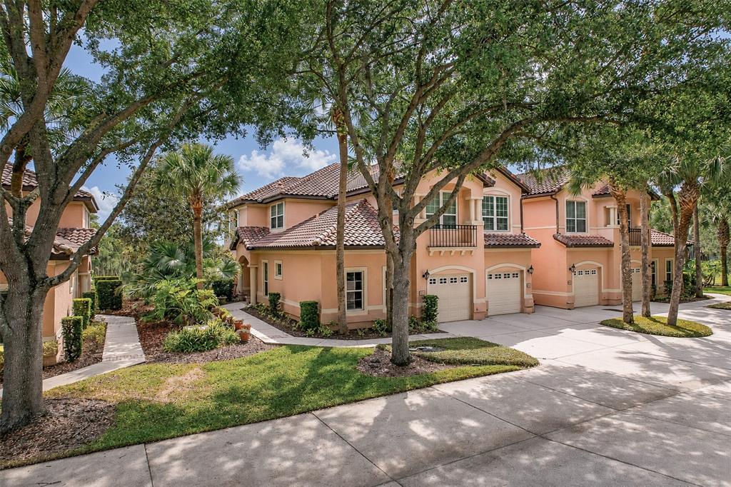 A multi-unit residential building with peach stucco walls, tile roofs, and attached garages — 901 CAMINO REAL BOULEVARD UNIT 901, HOWEY IN THE HILLS, FL