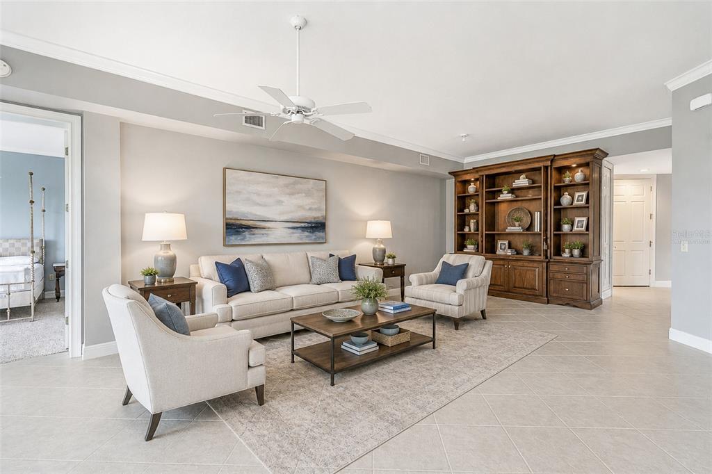 A living room features a beige sofa, two armchairs, a coffee table, and wooden shelving — 901 CAMINO REAL BOULEVARD UNIT 901, HOWEY IN THE HILLS, FL
