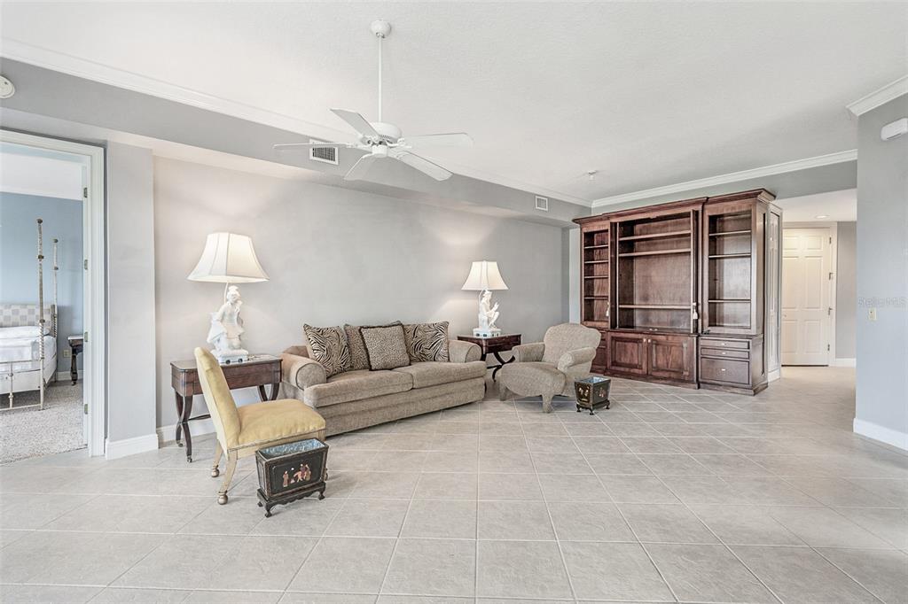 A living room features a beige sofa, an armchair, a wooden wall unit, and tile flooring — 901 CAMINO REAL BOULEVARD UNIT 901, HOWEY IN THE HILLS, FL