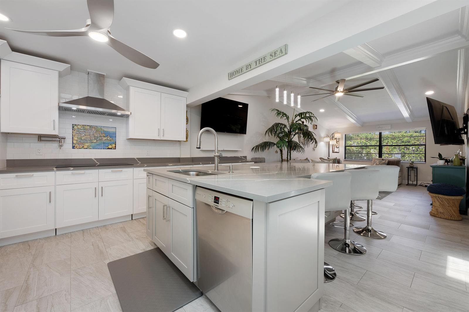 A modern white kitchen features a large island, stainless steel appliances, and light tile flooring — 7 Ridge Pointe Drive # C, Boynton Beach FL 33435, BOYNTON BEACH, FL