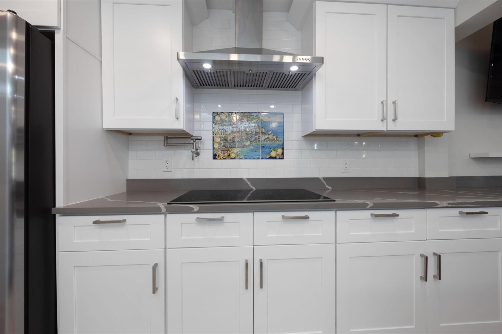 A kitchen features white cabinets, a gray quartz countertop, a subway tile backsplash, and a range — 7 Ridge Pointe Drive # C, Boynton Beach FL 33435, BOYNTON BEACH, FL