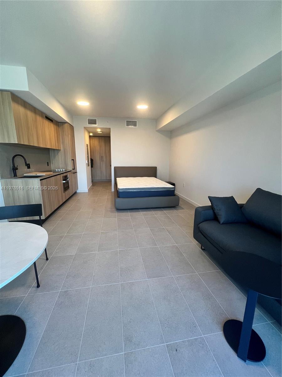 This studio apartment features a kitchen, living area, and bed on a tiled floor — 121 NE 5th st # 3400, Miami FL 33132, MIAMI, FL
