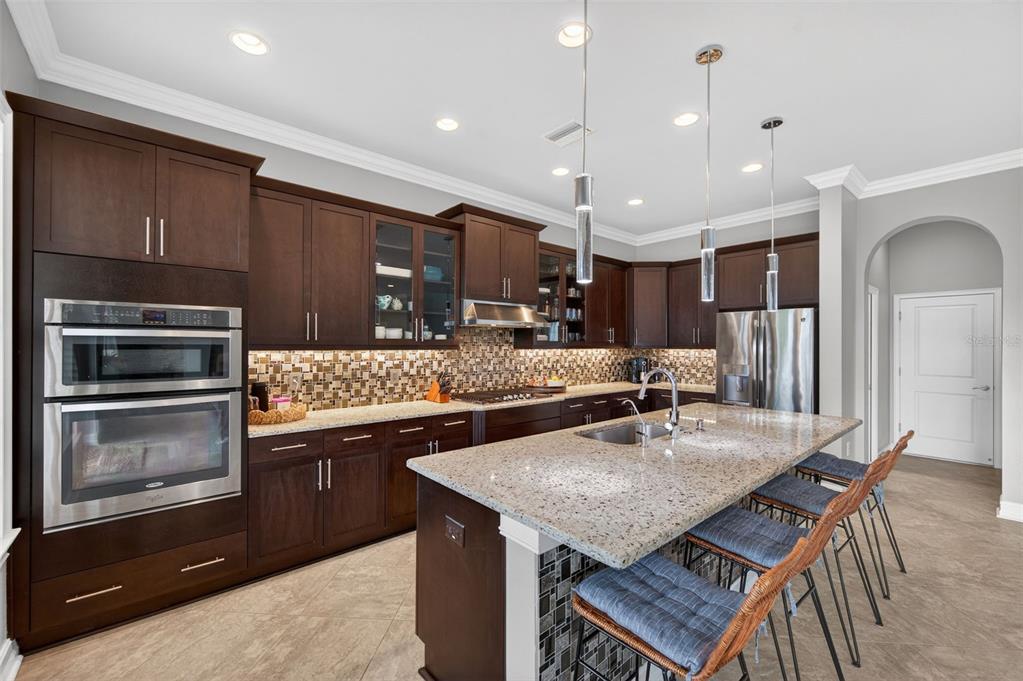 A kitchen with dark wood cabinets, granite countertops, stainless steel appliances, and a center island — 4020 EMPOLI COURT, WESLEY CHAPEL, FL