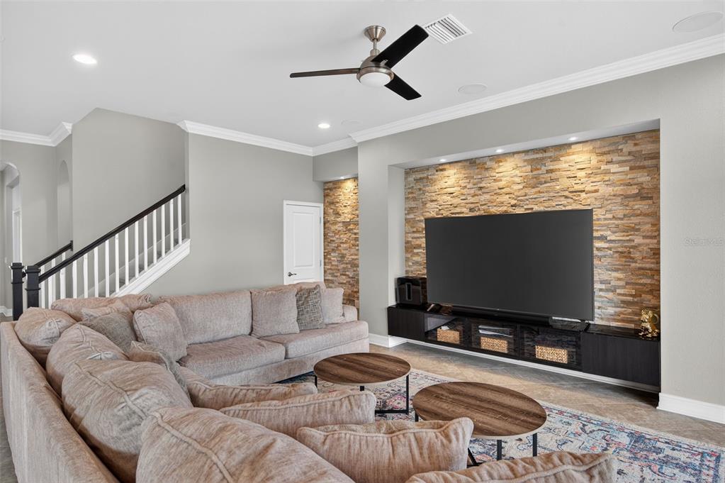 A living room features a large sectional sofa, a stone accent wall, and a ceiling fan — 4020 EMPOLI COURT, WESLEY CHAPEL, FL