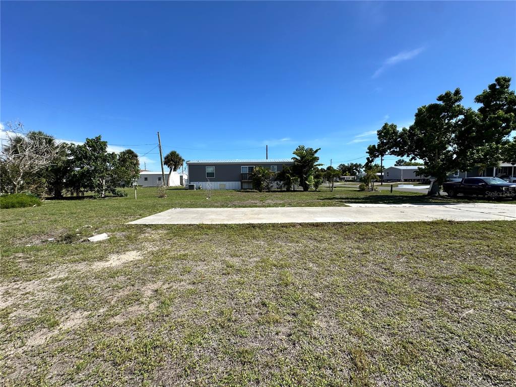A gray mobile home sits on a grassy lot with a concrete driveway in front — 1427 SEAGULL DRIVE, ENGLEWOOD, FL