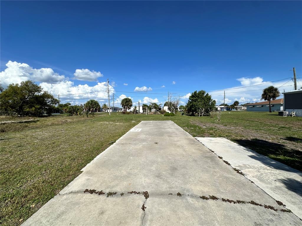 A concrete pad sits in a grassy lot under a clear blue sky — 1427 SEAGULL DRIVE, ENGLEWOOD, FL