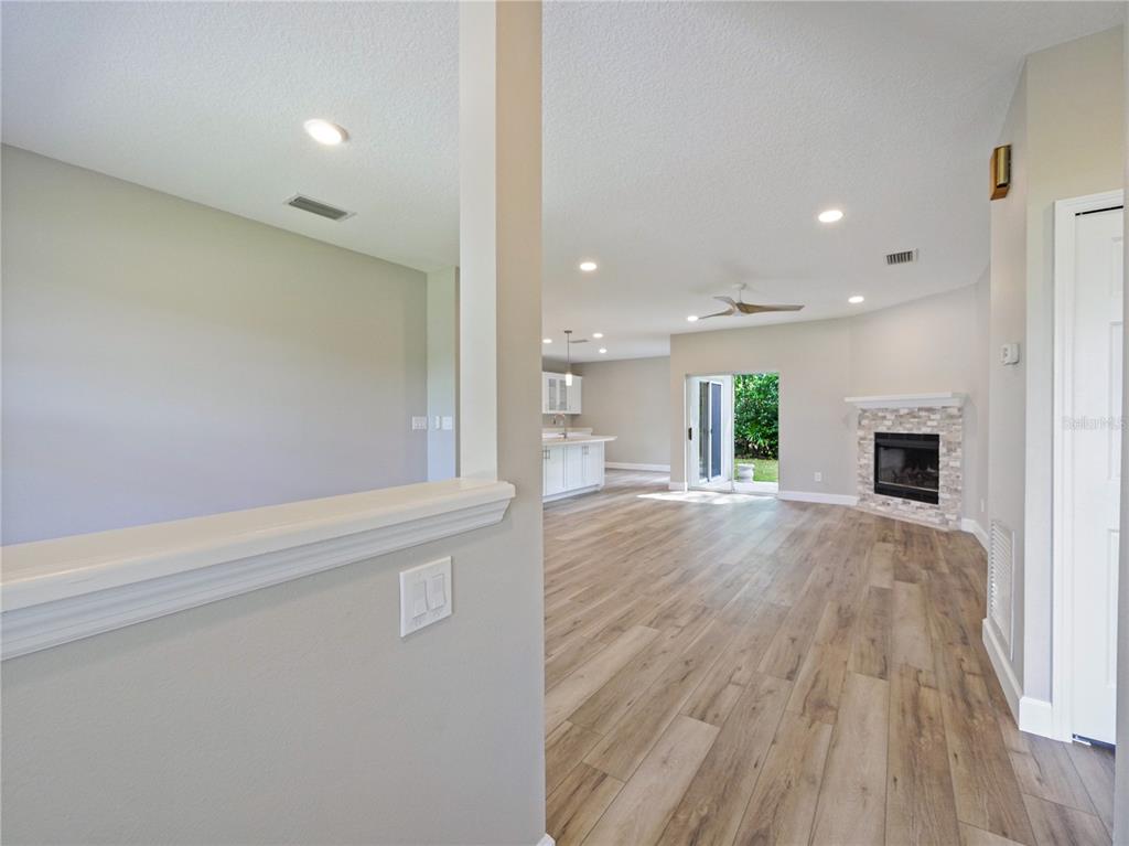 An open-concept living room with wood-look flooring, a stone fireplace, and a kitchen in back — 1801 FORMOSA AVENUE, ORLANDO, FL